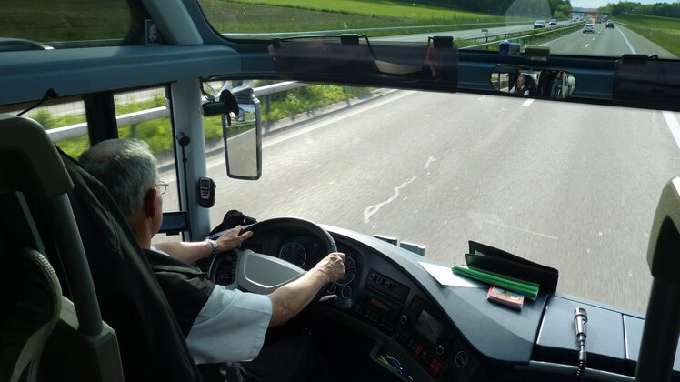 Ein Busfahrer, der einen Reisebus über die Autobahn fährt | © Hans Braxmeier auf Pixabay 