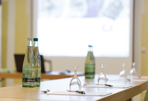 Detailansicht auf einen für Tagungen eingedeckten Tisch mit Block, Stift und Mineralwasser | © Frankenhotel Drei Kronen Memmelsdorf GmbH