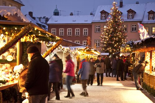 Menschen auf dem verschneiten Bamberger Weihnachtsmarkt, die die Auslagen der Stände betrachten | © Bamberg Tourismus